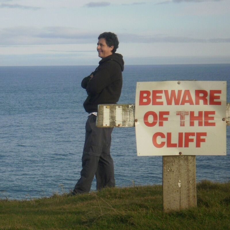 Barbel staring into space with a sign next to her saying beware the cliff
